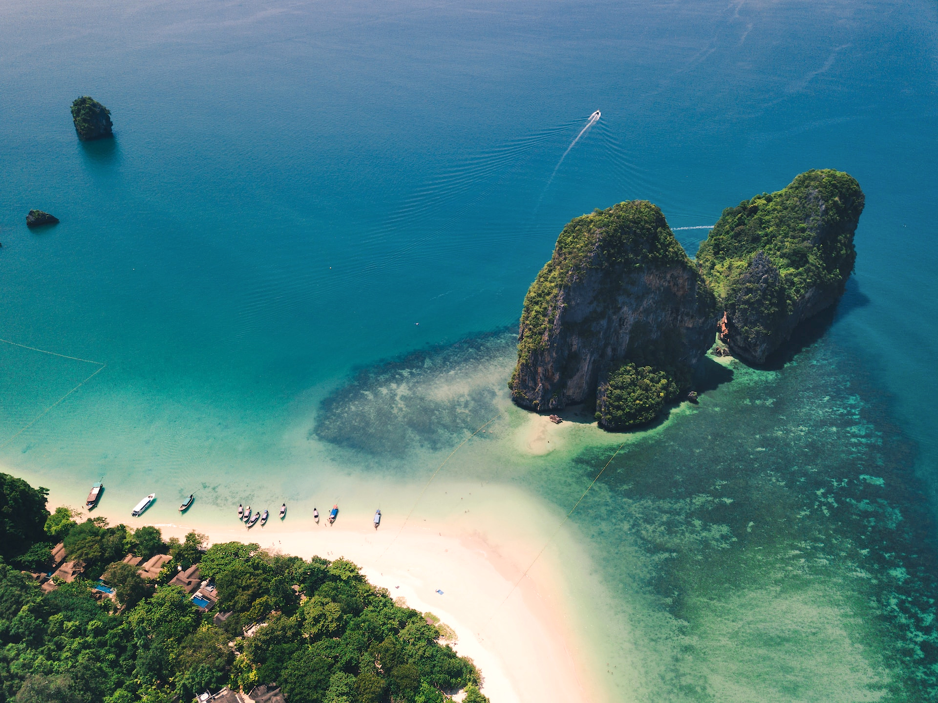 Droneudsigt over sandstrand og klart blåt hav i Phuket, Thailand. Tropisk landskabsfotografi med palmer og roligt hav.