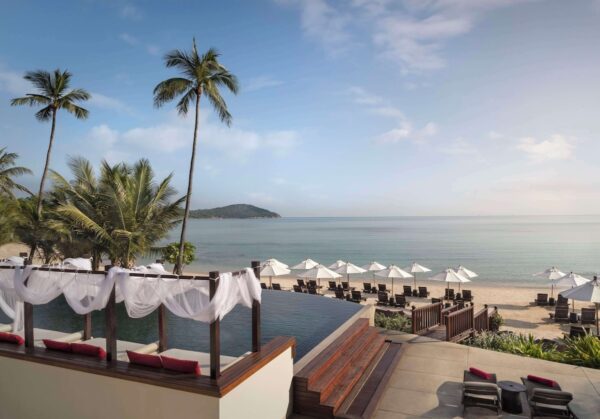 Pool med liggestole og parasoller med udsigt over stranden på Lawana Samui Resort