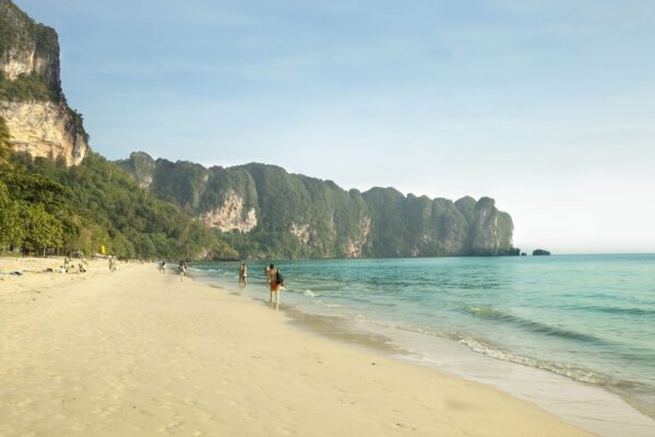 Aonang Beach med gående mennesker, klippeformationer og Villa Resort