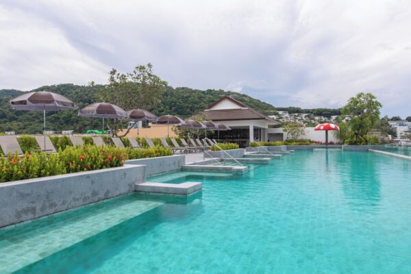 Nyd en lækker pooloplevelse på Khao Lak Laguna Resort med behagelig liggestole og paraplyer, alt sammen omgivet af betagende bjerge.