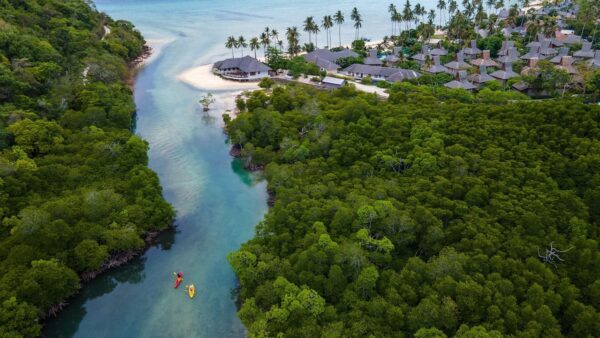 Phi Phi Island Village Beach Resort fra fugleperspektiv, beliggende på en tropisk ø med hvid sandstrand og turkisblåt hav. Forskellige